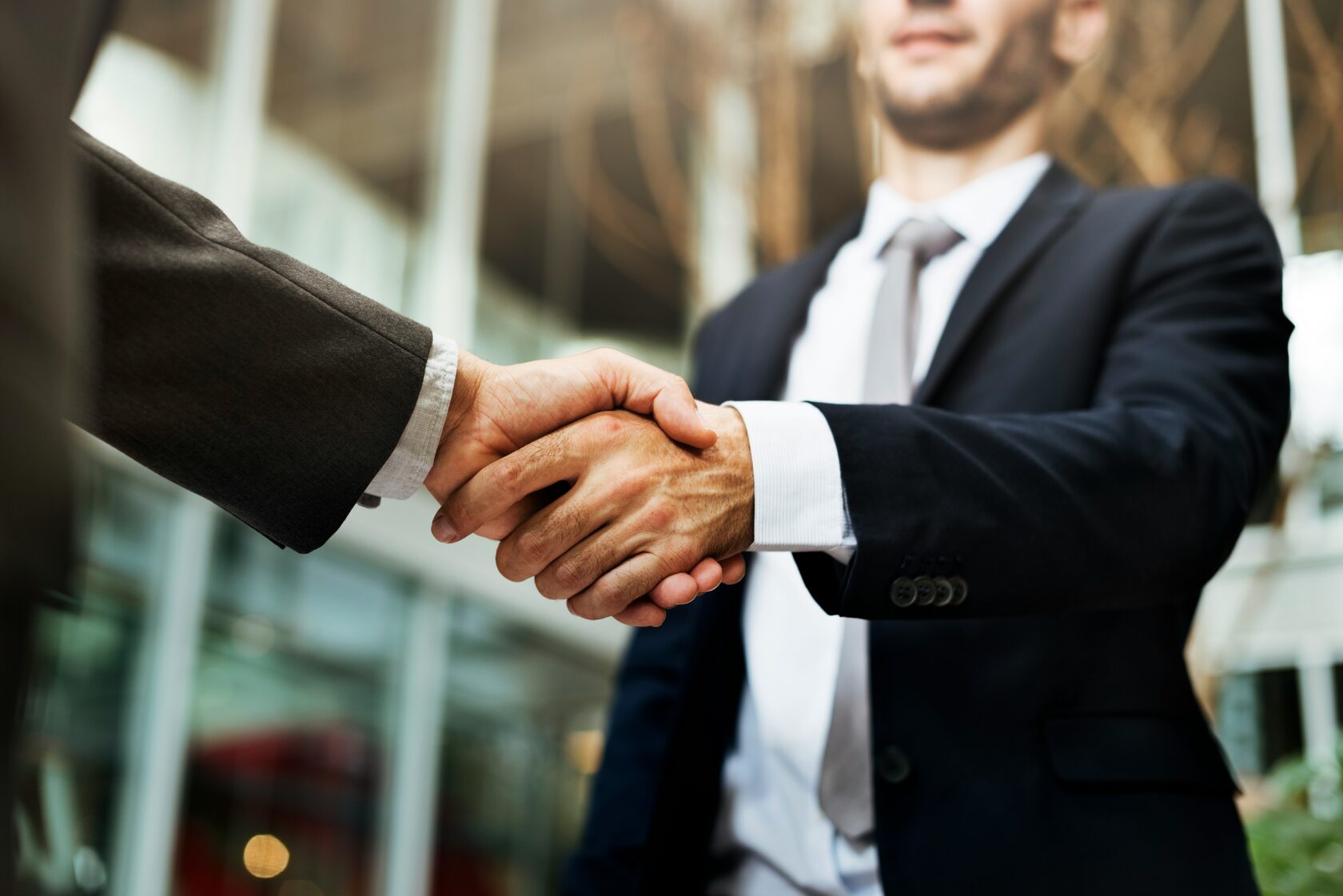 Two businessmen shaking hands outside an office building